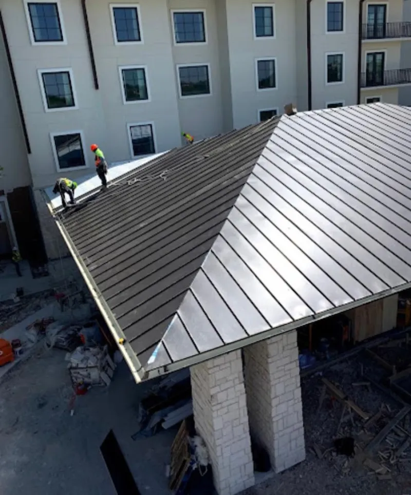 Crew installing standing seam metal roof panels on a commercial project in Hueytown